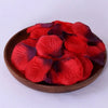 A pile of deep red and purple silk rose petals used for weddings and proposals.