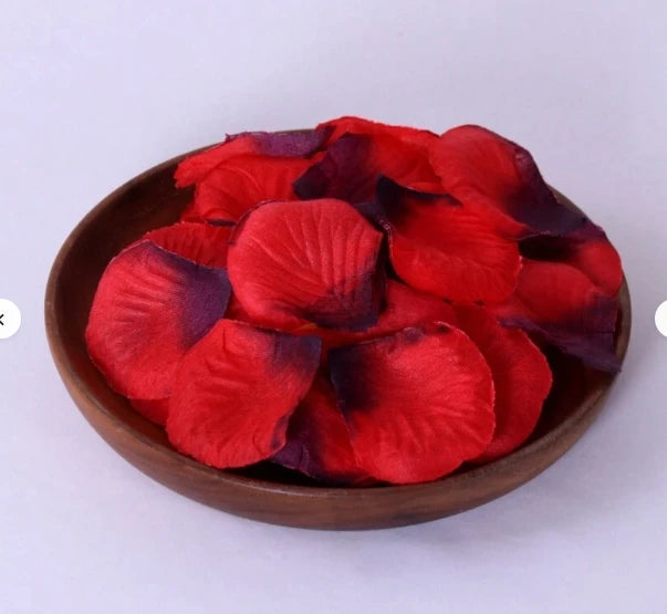A pile of deep red and purple silk rose petals used for weddings and proposals.