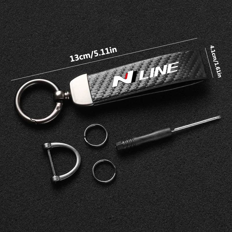 A black carbon fiber style leather keychain with a silver swivel buckle and a metal pin.