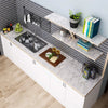 A kitchen countertop featuring a stainless steel sink and white cabinetry with marble-look surfaces.