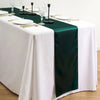 A white tablecloth with a dark green satin table runner and gold cutlery set for an elegant dining table.