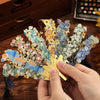 A hand holds a vintage metal bookmark with an artistic hollow design and tassel, featuring gold and blue elements.