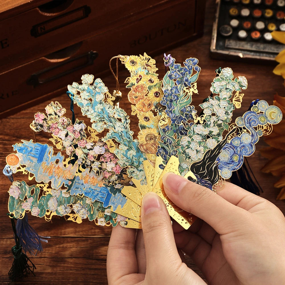A hand holds a vintage metal bookmark with an artistic hollow design and tassel, featuring gold and blue elements.