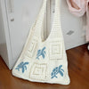 A white handwoven knit tote bag with a hollow design featuring blue elephant motifs, hanging in front of a white cabinet.