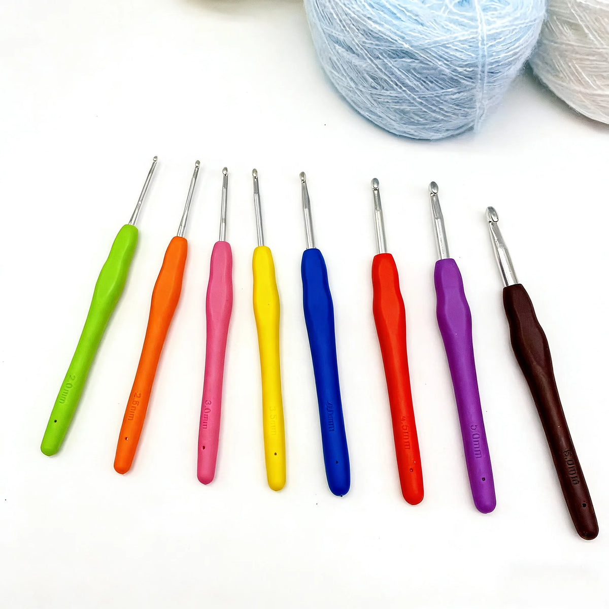 An arrangement of eight colorful crochet hooks and knitting needles in various sizes and colors on a white surface.