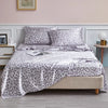 A luxury satin leopard print bedding set featuring gray and black spots on pillows and a duvet cover.