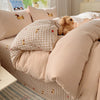 A beige duvet cover set with a plaid pattern and embroidered animals on a bed.