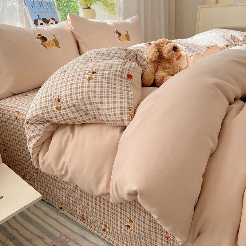 A beige duvet cover set with a plaid pattern and embroidered animals on a bed.