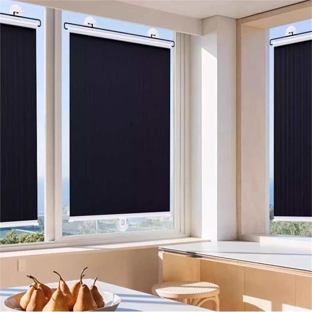 A window with a black retractable roller shade partially lowered, showing a bright outdoor view.