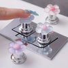 A set of elegant floral toilet flush handles in light blue and pink on a silver base.