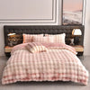 A pink faux fur duvet and pillow set displayed on a bed with a dark leather headboard.