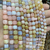 A hand holds a string of natural stone square faceted beads in various pastel colors for jewelry making