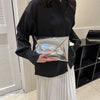A woman holds a silver crocodile pattern PU envelope clutch with a coin pocket against a black shirt and white skirt.