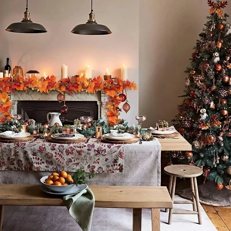An artificial maple leaf garland in orange and gold decorates a fireplace mantel and dining table setting.
