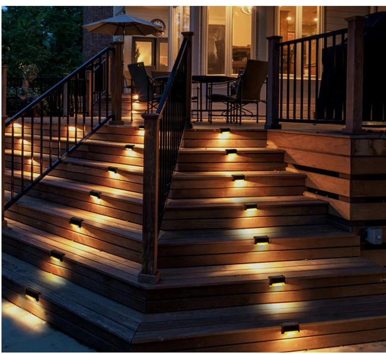 Outdoor stairs illuminated by solar powered LED lights on a wooden deck and railing.