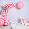 A display of pink and light blue balloons arranged in a curved wall decoration with a large pink balloon floating nearby.