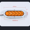An oval LED trailer tail light with a dynamic amber arrow turn signal mounted on a white plate.