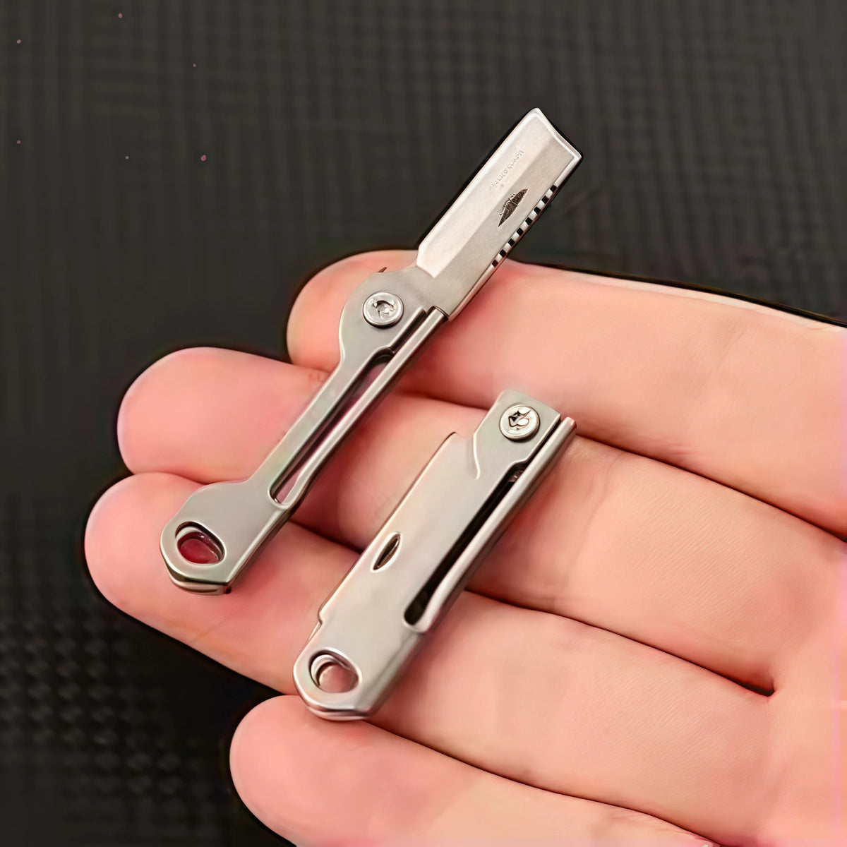 Une main tient un couteau de poche pliable argenté avec lame et poignée visibles.