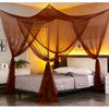 Elegant mosquito net bed canopy draped over a bed with sheer orange fabric.