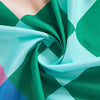 Green and teal plaid fabric draped in a swirl with rainbow accents