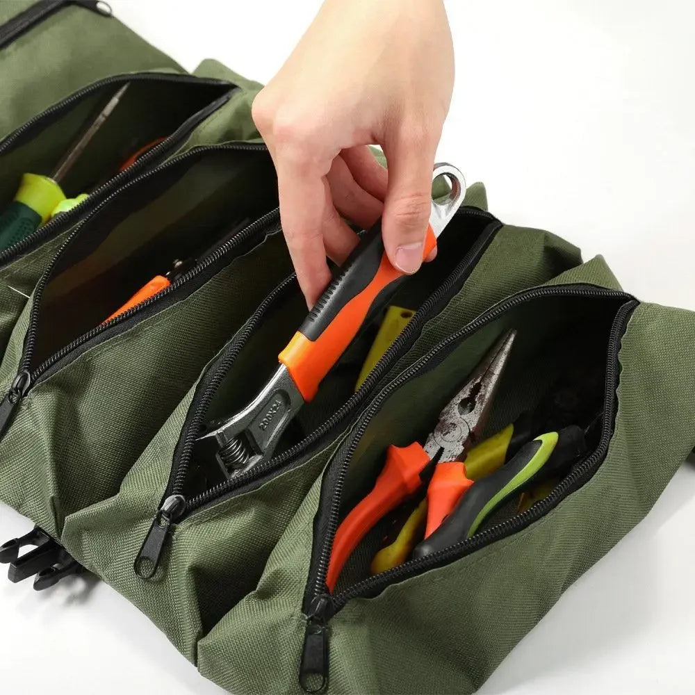 A hand is opening a green roll-up multi-pocket tool organizer bag revealing various small tools.