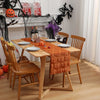 An autumn pumpkin and ghost themed table runner displayed on a wooden dining table.