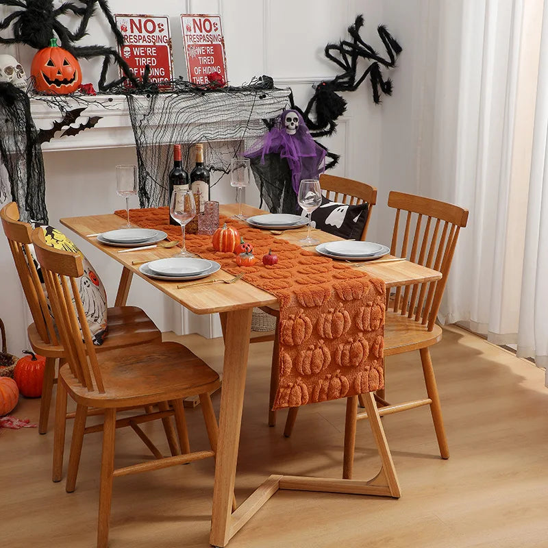 An autumn pumpkin and ghost themed table runner displayed on a wooden dining table.