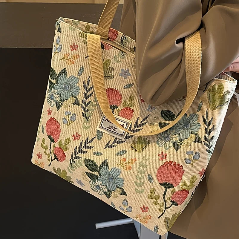 A beige corduroy tote bag with floral embroidery is shown hanging, featuring a light tan strap.