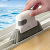 A hand is using a white cleaning brush to clean window tracks and tight spaces.