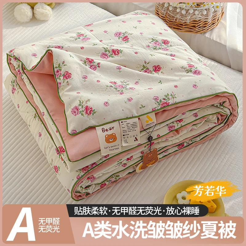 A lightweight summer quilt featuring a playful cartoon print in pink and white floral patterns.