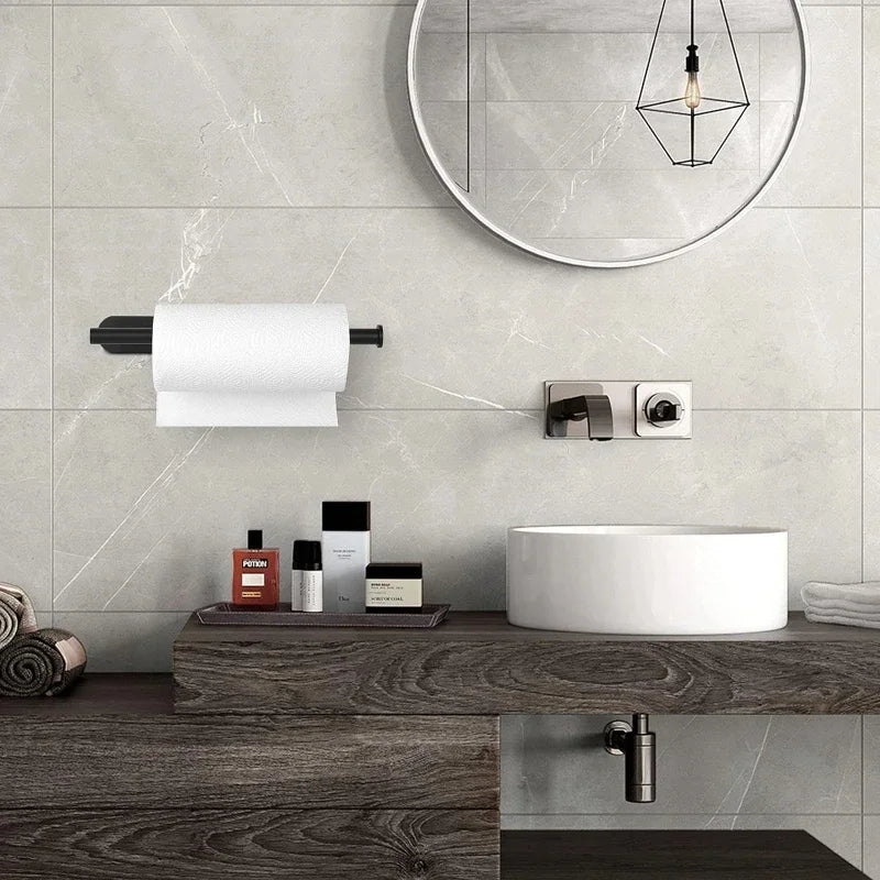 A stainless steel wall-mounted paper towel holder above a white vessel sink and mirror on a gray tiled wall.