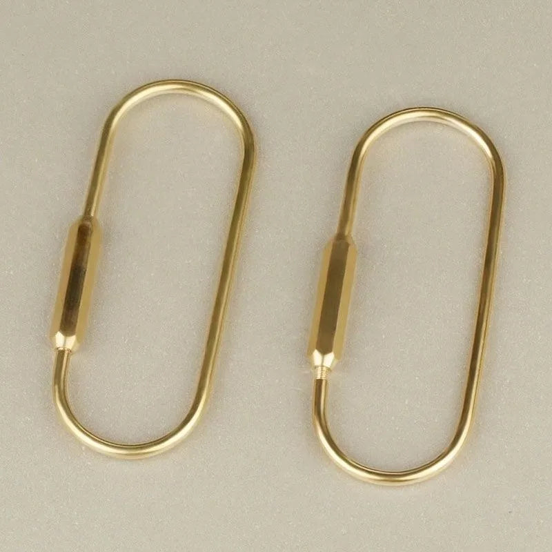 A pair of gold brass keychain charms with locking carabiner clips.