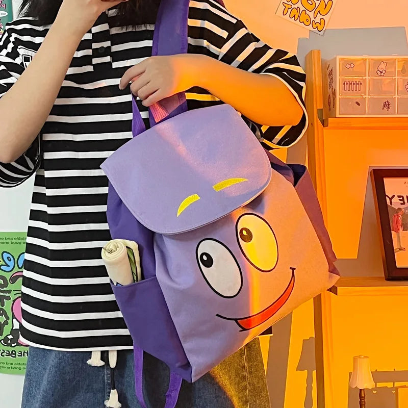 Eine Person hält einen lila Dora the Explorer Flanell-Rucksack vor einem orangefarbenen Hintergrund.