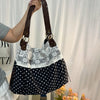 Une femme tient un sac à main patchwork noir et blanc à motifs floraux sur fond blanc.