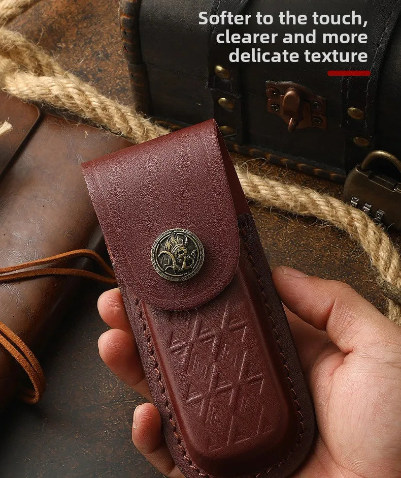 A hand holds a dark reddish-brown leather folding knife case with a decorative metal stud on top.