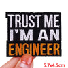 Black embroidered iron-on letter patch with white and orange text reading Trust Me I'm an Engineer