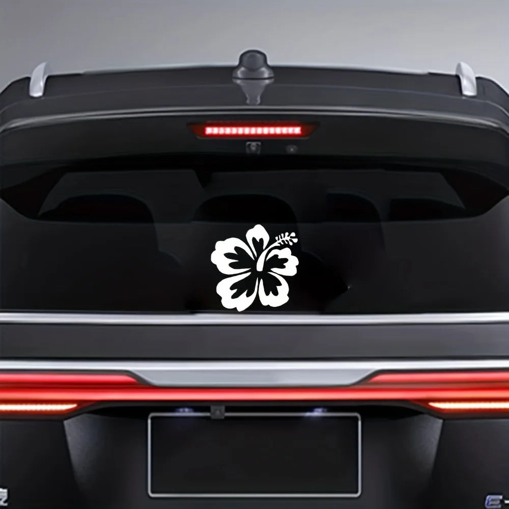 A black car rear view showing a white hibiscus flower decal sticker on the trunk and taillight area.