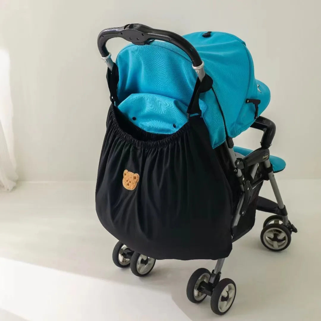 A black stroller organizer with bright blue and teal fabric storage bags on a wheeled frame.