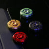 A collection of five magnetic fidget sliders in various colors including green, gold, silver, and red resting on a dark surfa