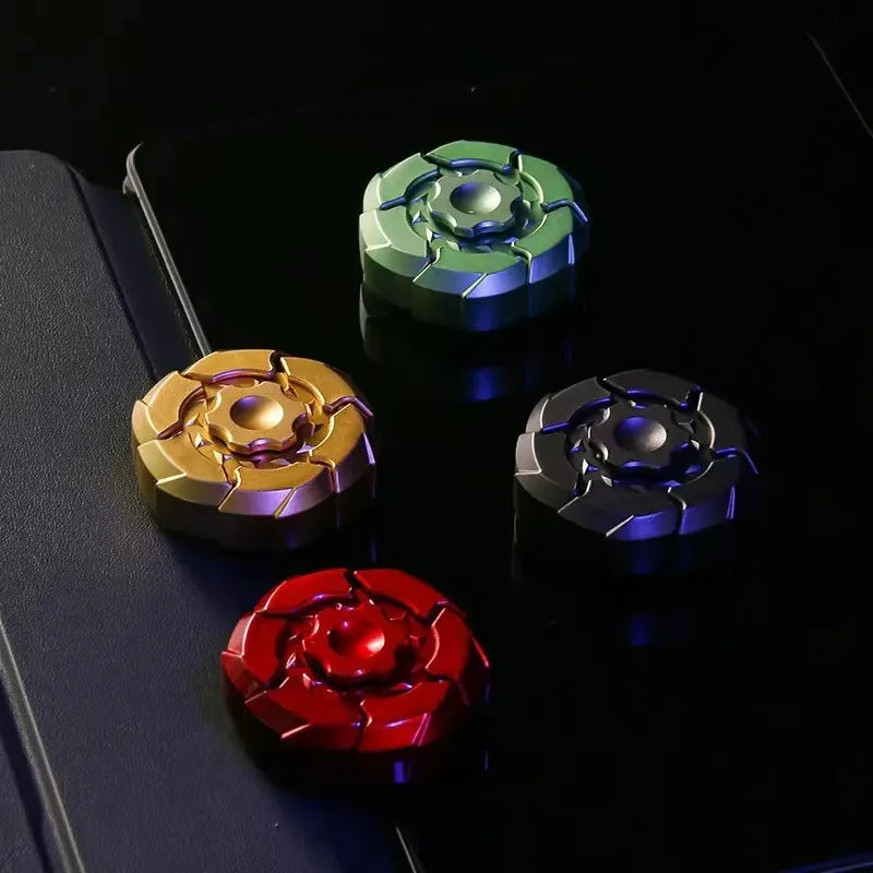 A collection of five magnetic fidget sliders in various colors including green, gold, silver, and red resting on a dark surfa