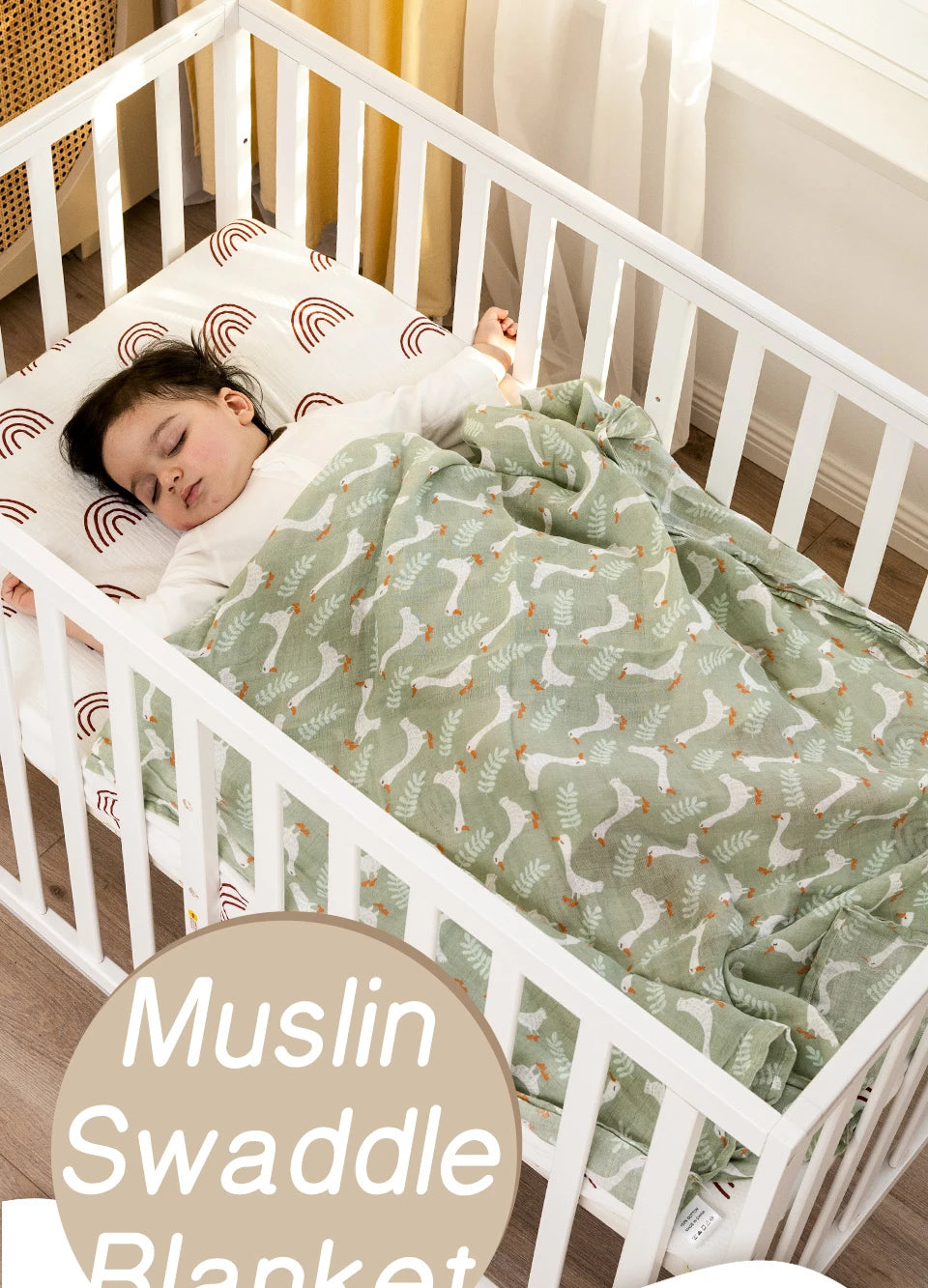 A baby is sleeping in a white crib wrapped in a green muslin swaddle blanket.