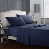 A navy blue bedding set featuring a fitted sheet, flat sheet, and pillows on a bed with a upholstered headboard.
