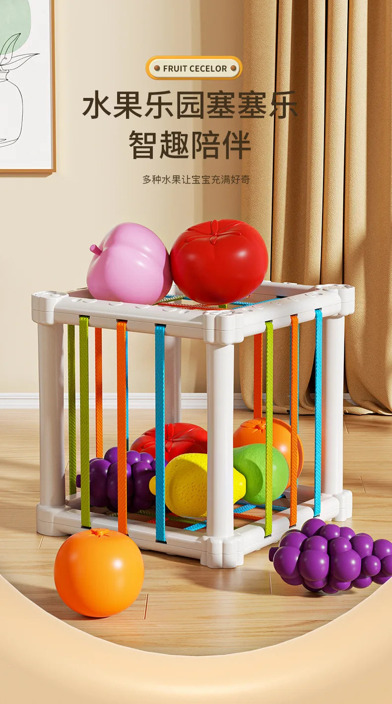 A white wooden fruit sorter cube with colorful elastic bands holding various fruits like apples and oranges.
