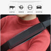 A close-up of a person wearing a black leather seat belt cover on a pink sweater, showing the strap detail.