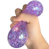 Eine Hand drückt einen lila glitzernden Squishy-Dumpling-Sensorspielzeug.