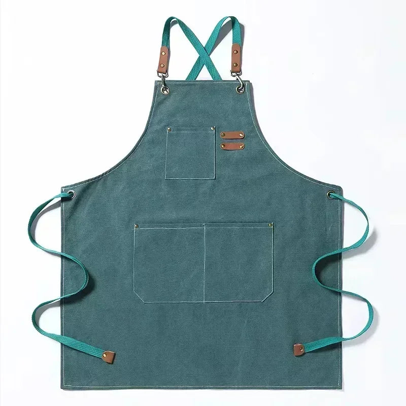 A teal cotton canvas apron with cross-back straps and multiple pockets.