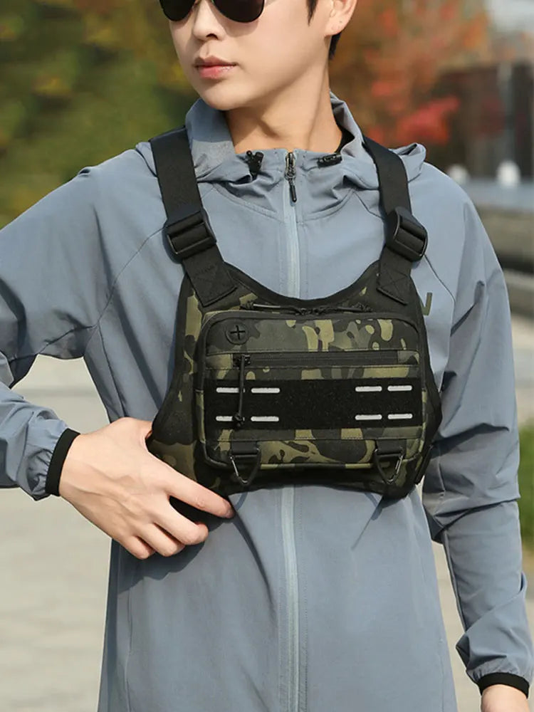 Ein junger Mann trägt eine helle blaue Jacke und hält einen schwarzen taktischen Brustgurt mit Laufvesttasche.