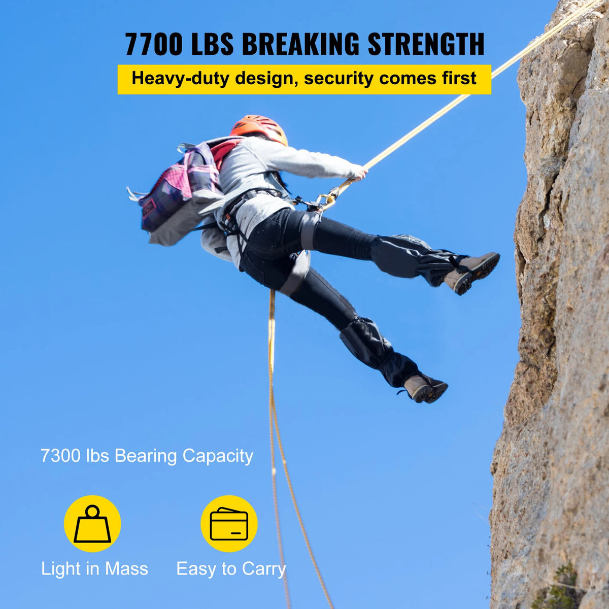 A person is using a heavy-duty breaking strength climbing rope system on a rock face under a clear blue sky.