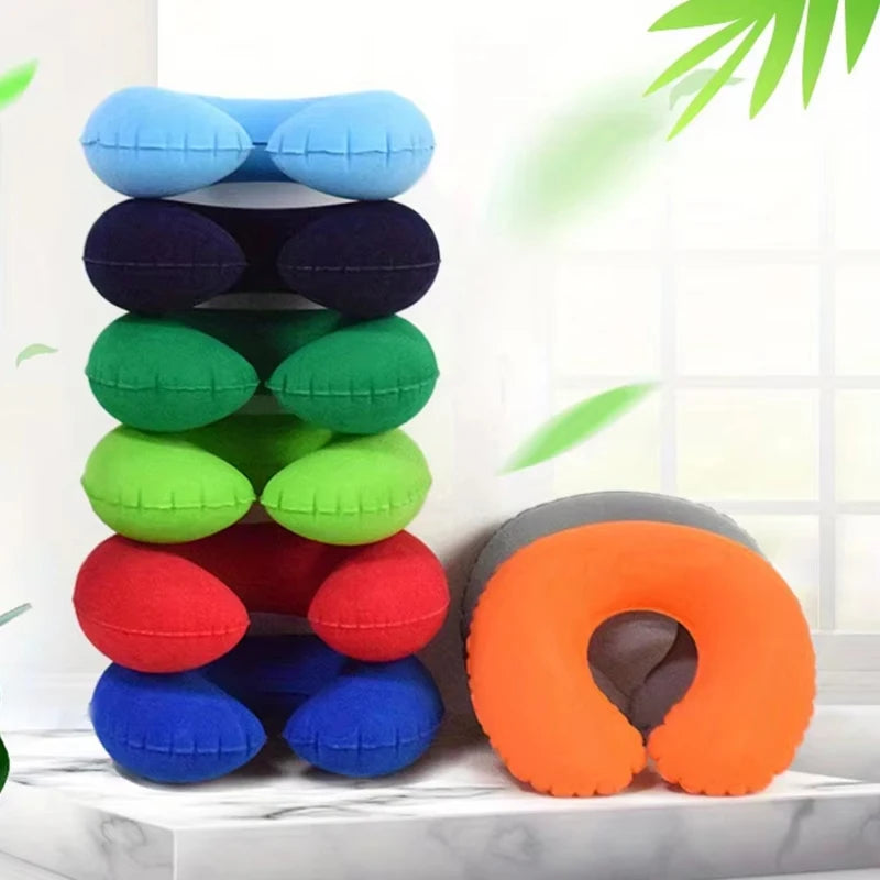 A stack of colorful inflatable U-shaped travel neck pillows in blue, purple, black, green, and red, next to an orange one.