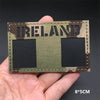 A rectangular tactical patch featuring the word IRELAND in distressed lettering on a camouflage background with two black squ